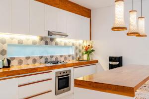 une cuisine avec des armoires blanches et un comptoir en bois dans l'établissement Villa Vana, Sitara Villa Group, à Seminyak