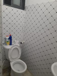 een wit betegelde badkamer met een toilet en een wastafel bij Mwembeni Abode in Bamburi