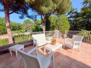 a patio with white chairs and tables and trees at Villa Vittorio a 4km dal mare in Trebbiantico