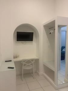 een witte kamer met een bureau en een tv aan de muur bij Abagnale Home Sorrento in Sorrento