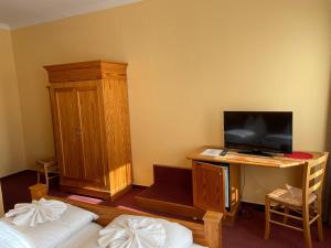 ラインスベルクにあるZum Jungen Fritz Gast- Logierhausのデスク、テレビ、キャビネットが備わる客室です。