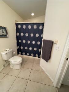 baño con aseo y cortina de ducha azul en Marco Island Retreat- close to beach !, en Marco Island