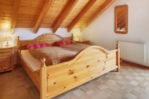 a bedroom with a large wooden bed with pink pillows at Fewo Cheny mit Hochschwarzwaldcard in Titisee-Neustadt +20 photos
