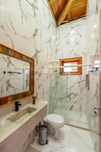 a bathroom with a toilet and a glass shower at Village das Estações in Marau