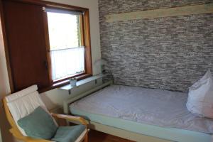 a bed and a chair in a room with a brick wall at Ferienhaus am Belmermoor 167 in Brunsbütelkoog