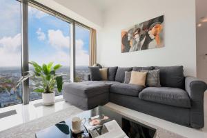 een woonkamer met een grijze bank en grote ramen bij Sky Tower Panorama Apartments in Wrocław