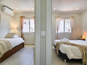 a bedroom with two beds and a hallway with two windows at Casa Safia - Beach & Center 200m, AC, WiFi in Carvoeiro