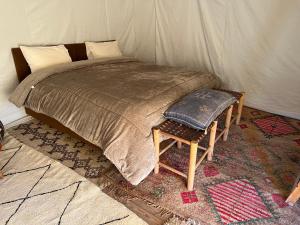 a bed with a pillow and a chair in a room at Across Sahara in Bou Nou