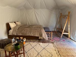 a bedroom with a bed and a table in a tent at Across Sahara in Bou Nou