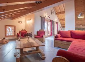 a living room with red couches and a wooden table at Ferme Le Coup d'Oeil in Taninges