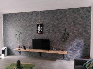 a living room with a tv on a brick wall at Getaway to Mauritius - Évasion à Île Maurice in Eau Bleue