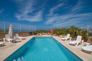 ein Swimmingpool mit Liegestühlen und Sonnenschirm in der Unterkunft Sublime Appart Neuf in Albitreccia