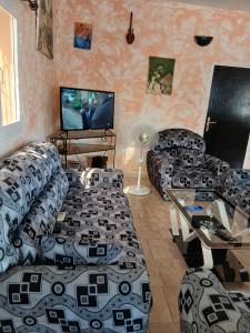 a living room with couches and a flat screen tv at Chez André Léon in Ngaparou