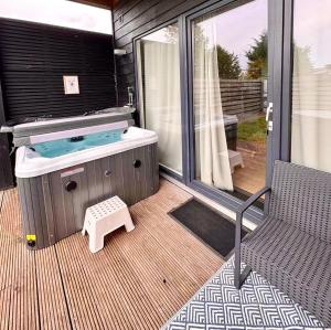 a hot tub on a deck with a bench at Family house with garden & jacuzzi & sauna near Amsterdam in Vijfhuizen