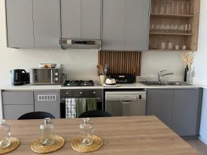 a kitchen with white cabinets and a wooden table at Modern Simons Town Apartment near beach and penguins in Simonʼs Town