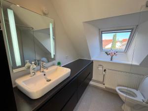 a bathroom with a sink and a mirror and a toilet at Large central townhouse, only 500m from Horsens city center in Horsens +6 photos