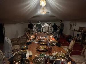 um grupo de pessoas em pé em torno de uma mesa em uma tenda em Across Sahara em Bou Nou