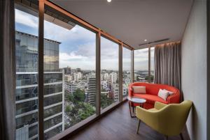a room with a red chair and large windows at Hyatt Place Dhaka Uttara in Dhaka