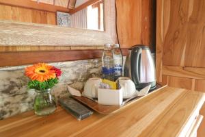 a counter with a vase of flowers and a tv at Mina Baturiti Hotel & Resto in Patjung