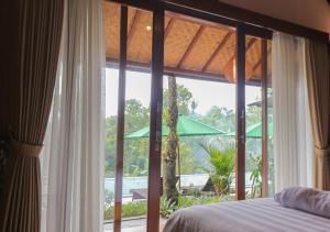 a bedroom with a bed and a large window at Mina Baturiti Hotel & Resto in Patjung