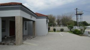a white building with a parking lot in front of it at Lilly Petals Guest House in Maun