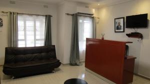 a living room with a chair and a flat screen tv at Lilly Petals Guest House in Maun