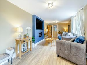 a living room with a couch and a tv at Lovetts Bridge Cottage in Atherstone