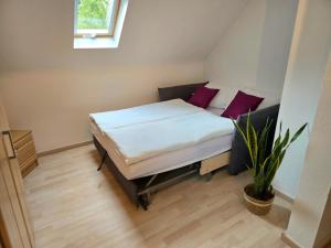 a small bedroom with a bed with purple pillows at Ferienhäuschen in Dickesbach in Dickesbach