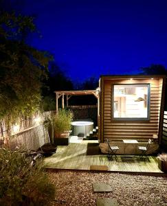 une petite cabane en bois avec une table et des chaises la nuit dans l'établissement Tiny house with garden and jacuzzi near Amsterdam, à Vijfhuizen