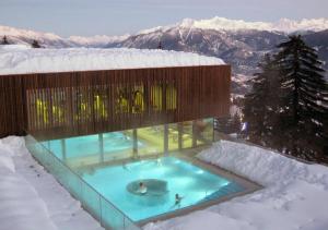un bâtiment avec une piscine dans la neige dans l'établissement Les Cerfs - Appartement & Studio - ANZERE, à Anzère