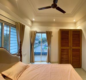 a bedroom with a bed with a ceiling fan and a window at Go-kul Homestay in Kolhapur