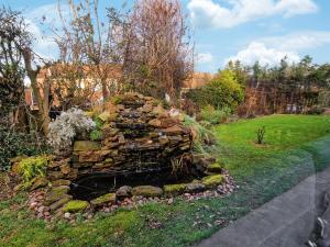 eine Steinmauer mit einem Teich im Gras in der Unterkunft Forest View Cottage in Nottingham