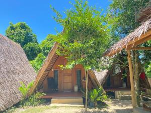 a house with thatched roofs and a tree at RCM Ecolodge Inn in San Juan
