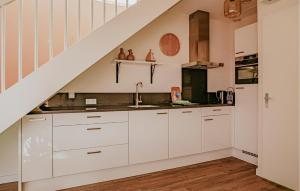 a kitchen with white cabinets and a staircase at Saskerlei in Uitgeest