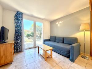 a living room with a blue couch and a window at Les Deux Terrasses, 6 pers Piscine à Calvisson in Calvisson