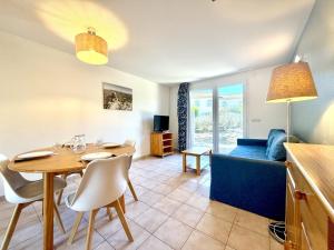 a living room with a table and a blue couch at Les Deux Terrasses, 6 pers Piscine à Calvisson in Calvisson