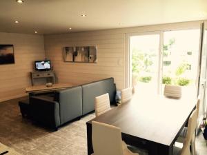 een woonkamer met een bank, een tafel en een televisie bij Maison proche mer Langueux in Langueux