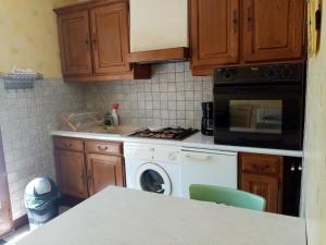 a kitchen with a stove and a washing machine at petunias in Vic-sur-Cère