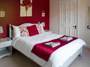 a bedroom with a large white bed with red walls at Ash Cottage E1224 in Winthorpe