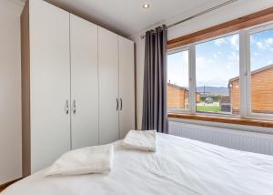 a bedroom with a bed and a large window at Castlewood Lodges in Strachan