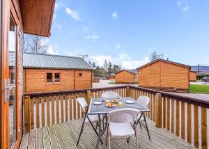 a patio with a table and chairs on a deck at Castlewood Lodges in Strachan