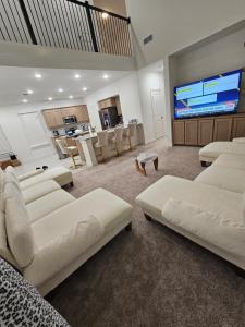 a living room with white couches and a large screen at Talia Heaven in Mesquite