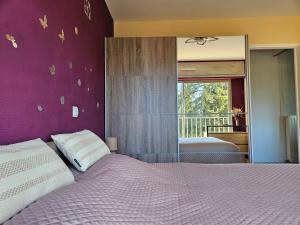 ein Schlafzimmer mit einem großen Bett mit einer lila Wand in der Unterkunft Idéal long séjour, Souvenirs de Provence,T2 classé, vue sur les montagnes, toutes commodités! in Digne-les-Bains