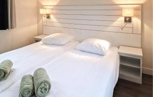 a white bed with two pillows and towels on it at Bodelaeke-Wiedenwoning in Giethoorn +7 photos