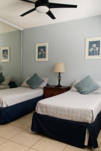 a bedroom with two beds and a ceiling fan at Ocean Terrace 202 a 4 min walk to Sandy Beach in Aguada