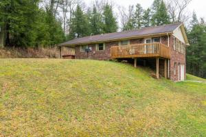 ein Backsteinhaus mit Terrasse über einem Feld in der Unterkunft Hot Tub & WiFi -Carrie's Cottage - Red River Gorge in Pine Ridge