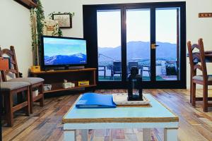 Una sala de estar con un televisor y una mesa. en Ca la Nena Morena - Refugio cálido con chimenea y vistas al Montseny, en Vallgorguina