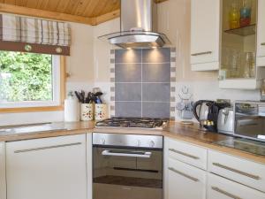 a kitchen with white cabinets and a stove top oven at Badger Lodge in Burton