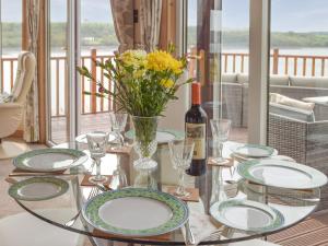 a glass table with plates and a bottle of wine at Badger Lodge in Burton