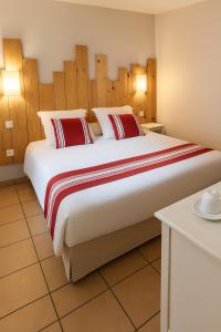 een groot bed met rode en witte kussens in een kamer bij Appartements au coeur du golf, proche du lac et vélodyssée in Biscarrosse